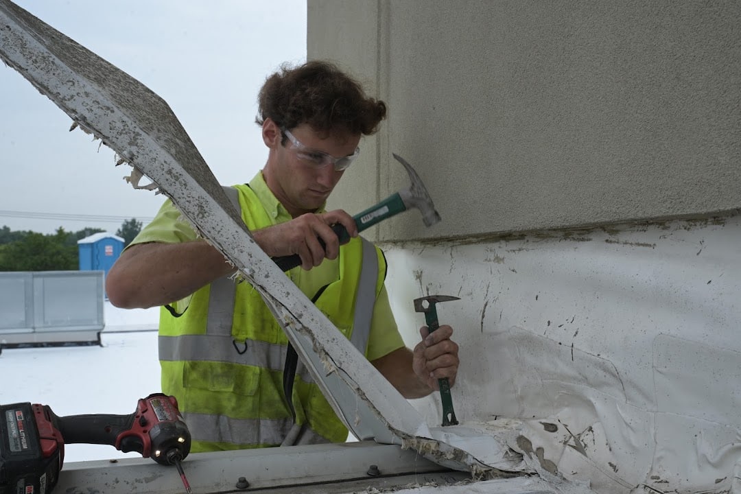 Green Improvements roofer applying sealant beneath a wall cap
