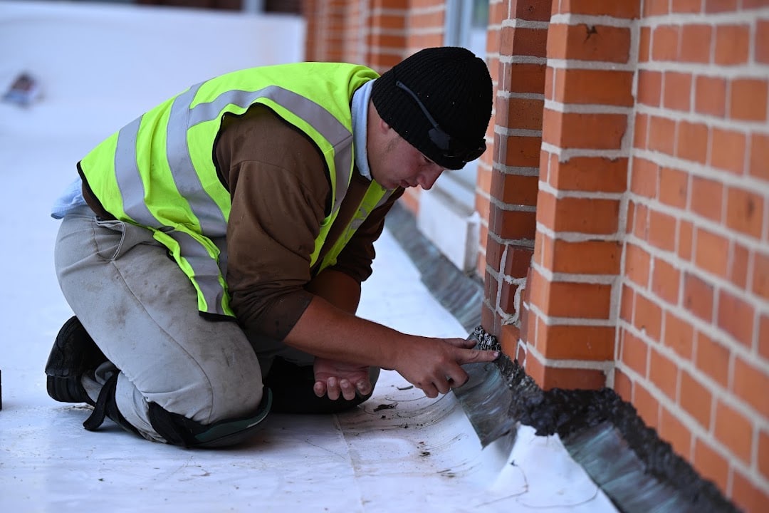 Green Improvements roofer securing flashing along a brick wall